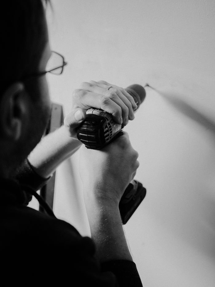 gallery-04 Black and white photo of a man using a drill for home improvement.