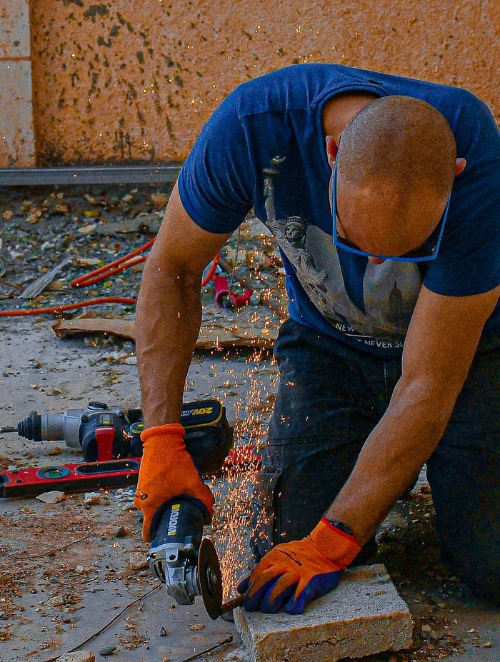 featured-images-04 A man using an angle grinder, creating sparks as he works on a construction site.